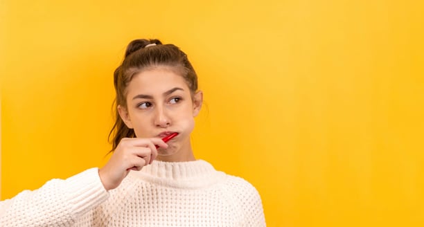 young woman brushing her teeth on yellow background